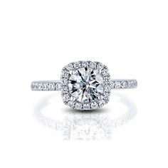 an engagement ring with a cushion shaped diamond surrounded by pave set round brilliant diamonds