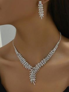 a woman wearing a necklace and earring set with crystal stones on the neck,