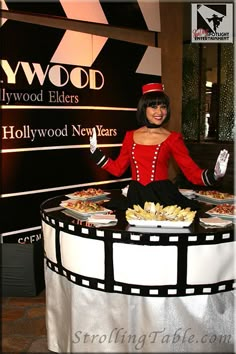 a woman dressed as a movie character standing in front of a table with food on it