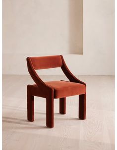 an orange chair sitting on top of a hard wood floor next to a white wall