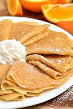 pancakes with whipped cream and oranges on the side are ready to be eaten for breakfast