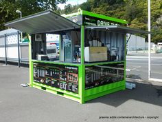 a green and white kiosk sitting on the side of a road next to trees