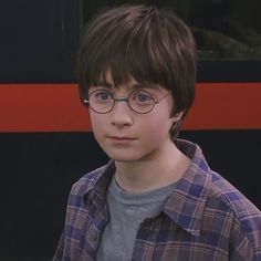 a young boy wearing glasses and looking at the camera