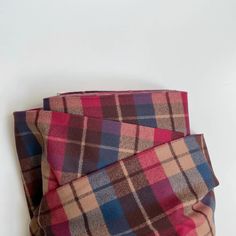 two pieces of plaid fabric folded on top of each other in different colors and patterns