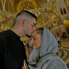 a man and woman standing next to each other in front of a building with gold decorations