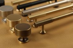 several different types of brass furniture knobs and pulls on a table top with gold leather