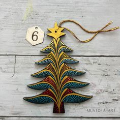 a wooden christmas tree ornament hanging from a string on a white wood background