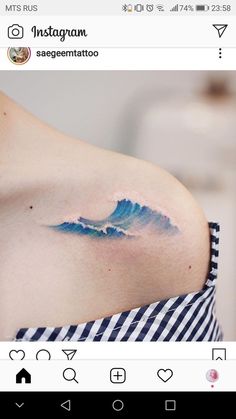 a blue wave tattoo on the back of a woman's left shoulder and chest