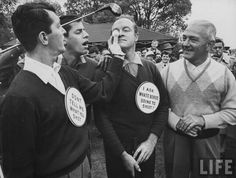 black and white photograph of men in uniform talking to each other with protest signs on their shirts