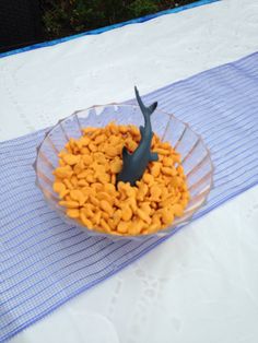 a bowl filled with fish crackers on top of a blue and white table cloth