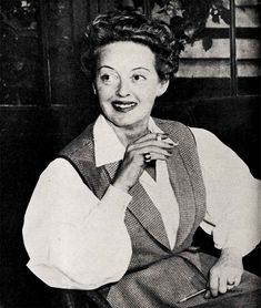 an old black and white photo of a woman sitting in a chair with her hand on her chin