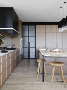 a kitchen with two stools next to a counter top and an island in the middle