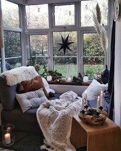 a living room filled with lots of furniture next to a window covered in blankets and candles