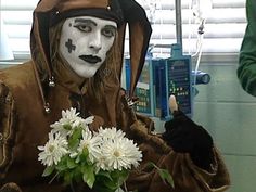 a man dressed in costume holding a vase with flowers