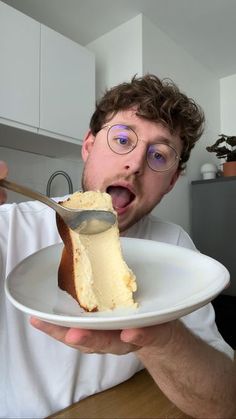 a man is holding a plate with a piece of cake on it and eating it