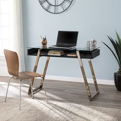 a desk with a laptop on it and a chair in front of it next to a clock