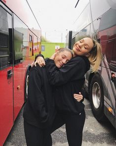 two women hugging each other in front of a bus