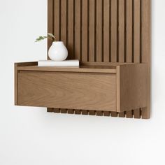 a white vase sitting on top of a wooden shelf next to a wall mounted shelf