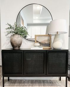 a black dresser with two vases on top and a mirror in the corner above it