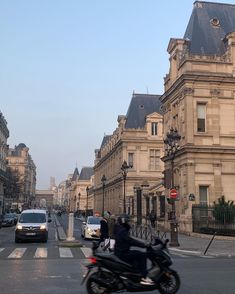 a motorcyclist is driving down the street in front of some old buildings