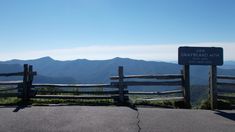 a wooden fence on top of a hill with mountains in the background