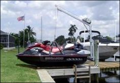 two jet skis parked next to a boat in the water near a dock and palm trees