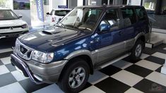 an suv is parked in a showroom next to other cars on the checkered floor