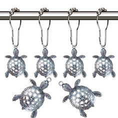 four sea turtle key chains hanging from a bar with hooks on it's sides