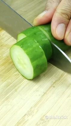 a person cutting up a cucumber with a knife