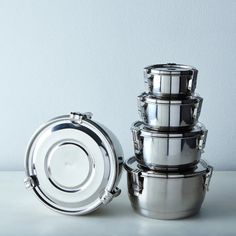 four stainless steel pots stacked on top of each other, with the lids open and one empty