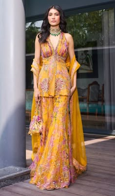 a woman in a yellow dress standing next to a pole with her hand on her hip