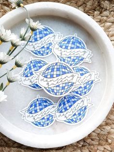 blue and white stickers on a plate with flowers in the bowl next to it