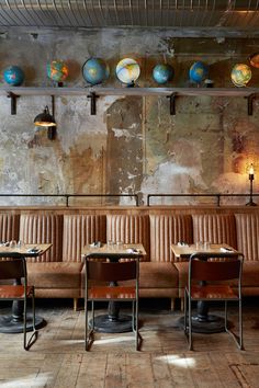 an empty restaurant with tables and chairs in front of a wall that has globes on it