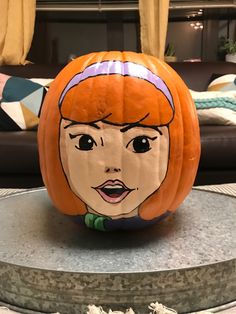 a pumpkin with a face painted on it in the shape of a woman's head