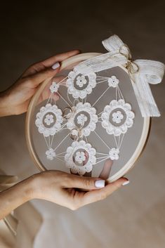 two hands are holding a white embroidered object