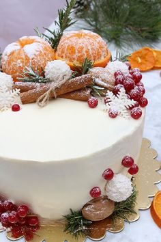 a white frosted cake with oranges and cranberries on the top is surrounded by other decorations