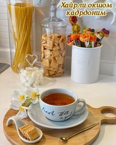 a cup of tea sits on a plate next to some crackers and cereals