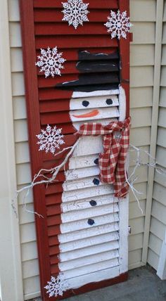 a snowman made out of shutters on the side of a house