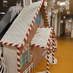 three gingerbread houses with candy canes on the roof and snowflakes hanging from the ceiling