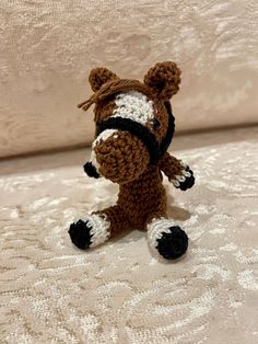 a small crocheted horse sitting on top of a bed