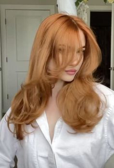 a woman with long red hair is standing in front of a mirror wearing a white shirt