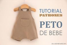 a baby bib with a wooden hanger hanging from it's side and the words peto de bebe written in spanish