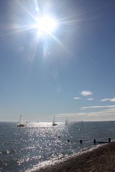 the sun shines brightly over an ocean with sailboats