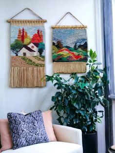 two woven wall hangings on the wall above a white couch in front of a potted plant