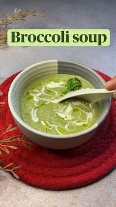 broccoli soup in a white bowl on a red place mat with a spoon