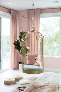 a pink bedroom with a birdcage bed and pillows on the floor next to it