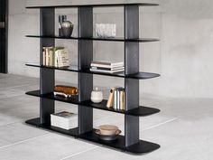 a book shelf with books and other items on it in an empty room that appears to be concrete