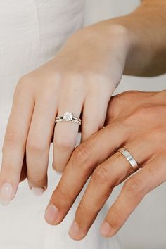 two people holding hands with wedding rings on their fingers and the other hand wearing a diamond ring