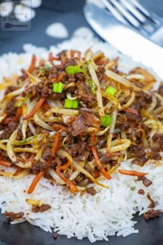 a black plate topped with white rice and meat