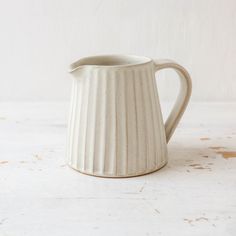 a white ceramic pitcher sitting on top of a table